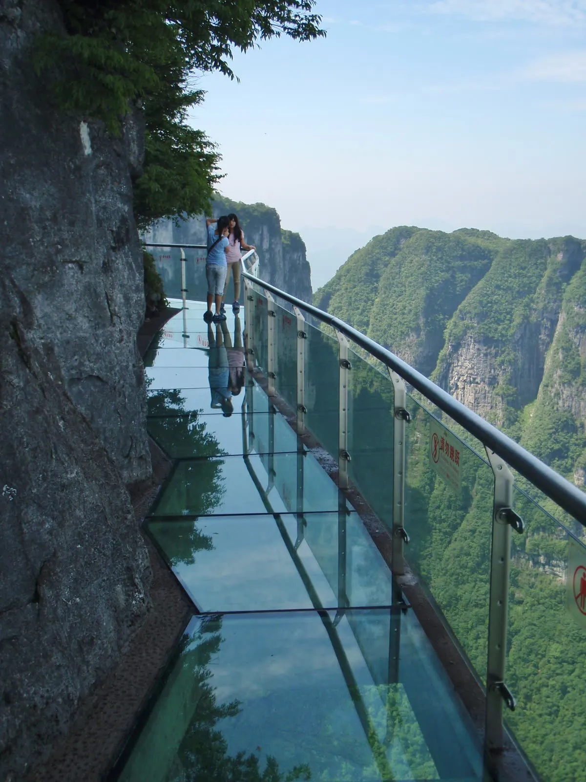 Visitors on the glass walkway attached to a vertical cliff face on Tianmen Mountain